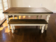 Load image into Gallery viewer, Straight-on view of farmhouse dining table and matching bench near a glass door on dark hardwood flooring