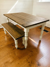Load image into Gallery viewer, Corner view of dark walnut farmhouse table and matching bench on hardwood flooring beside a shiplap wall
